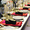 Modern red, black and white place settings at a long rectangle guest table with floral centerpieces